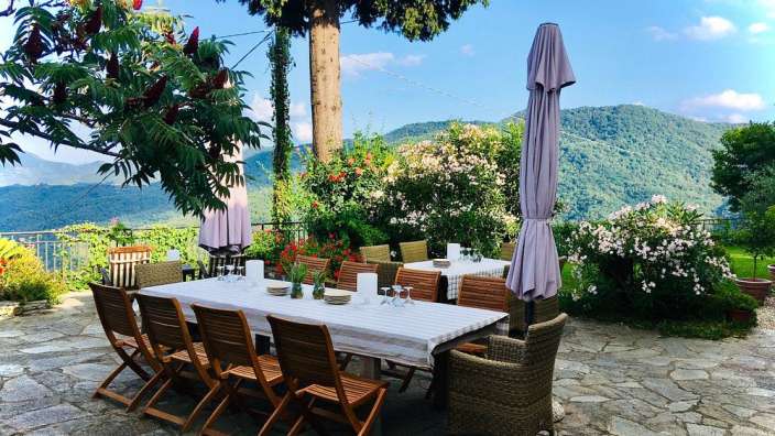 Ein Tisch und Stühle auf einer Terrasse mit Blick auf die Berge