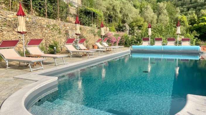 Liegestühle und Sonnenschirme umgeben einen großen Swimmingpool