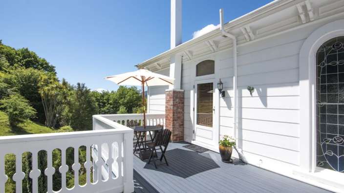 Ein weißes Haus mit einem Balkon mit Tisch und Stühlen