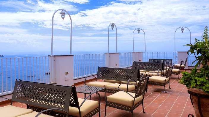 Eine Terrasse mit Möbeln und einem Tisch mit Blick auf das Meer