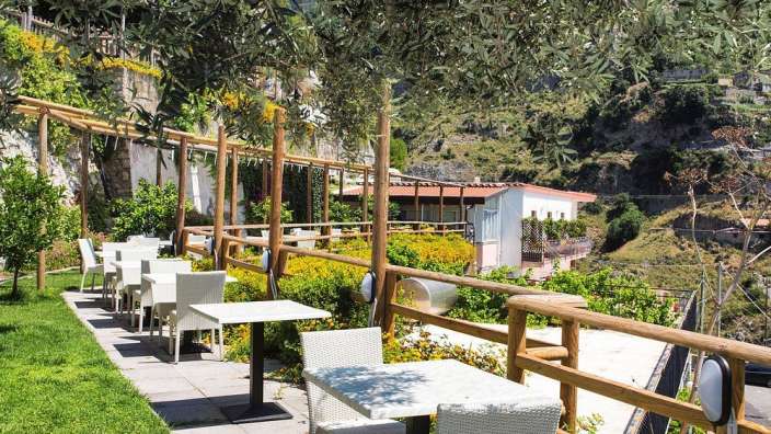 Eine Reihe von weißen Tischen und Stühlen neben einem Holzzaun