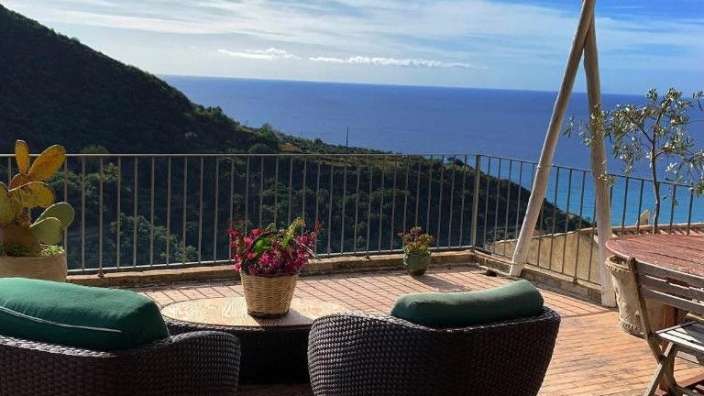 Zwei Stühle und ein Tisch auf einem Balkon mit Blick auf den Ozean .