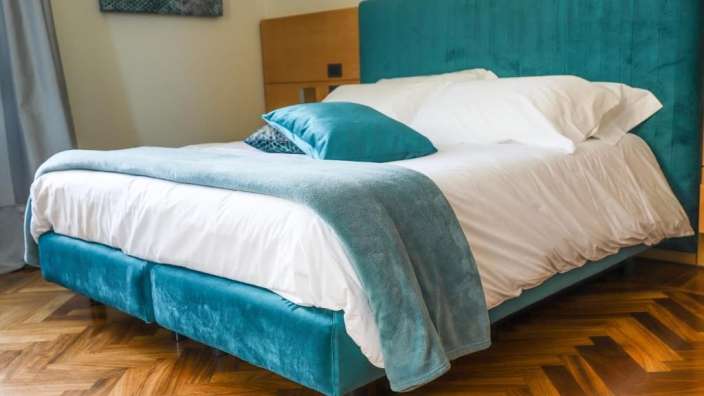 Ein Bett mit blauem Kopfteil und weißen Bettwäschen