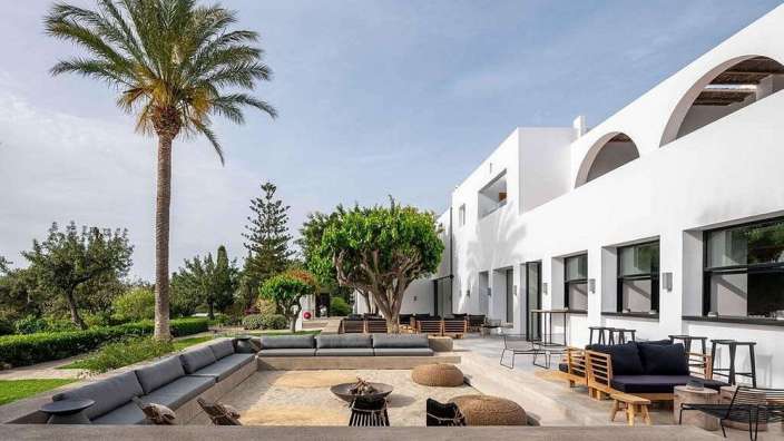 Ein weißes Gebäude mit vielen Möbeln und einer Palme