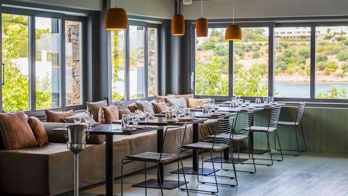 Eine Reihe von Tischen und Stühlen in einem Restaurant mit Blick auf einen See