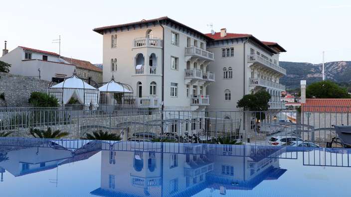 Ein großes weißes Gebäude spiegelt sich in einem Pool