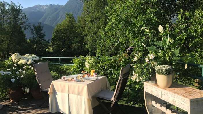Ein Tisch und Stühle auf einem Balkon mit Blick auf die Berge