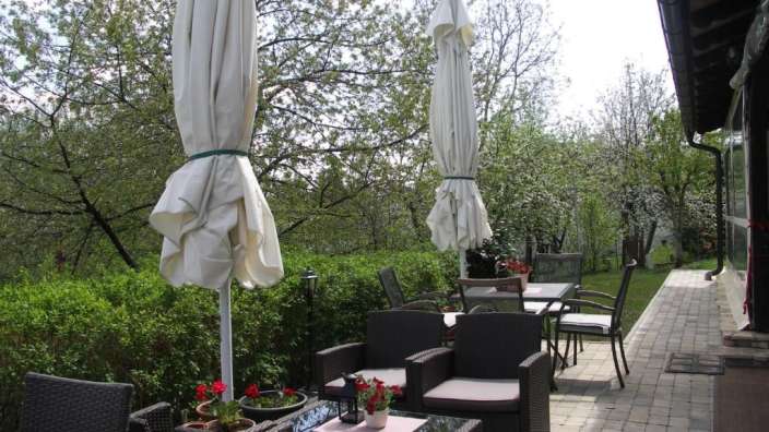 Eine Terrasse mit Möbeln und weißen Sonnenschirmen