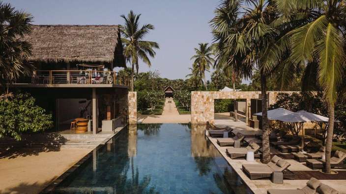 Ein großer Swimmingpool umgeben von Liegestühlen und Palmen