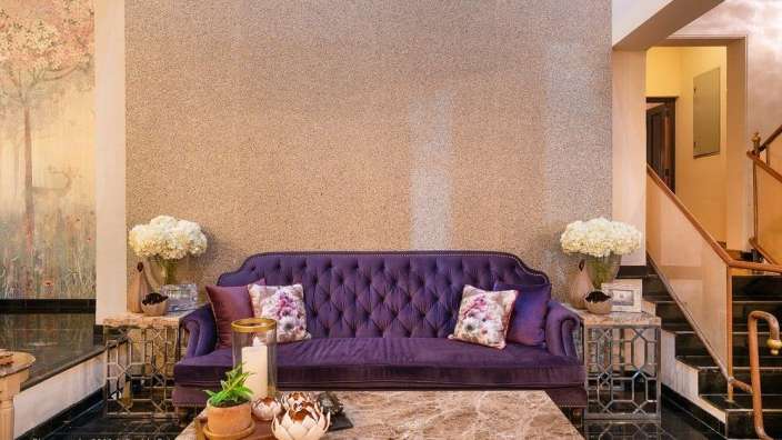 Ein Wohnzimmer mit einer lila Couch und einem Marmortisch