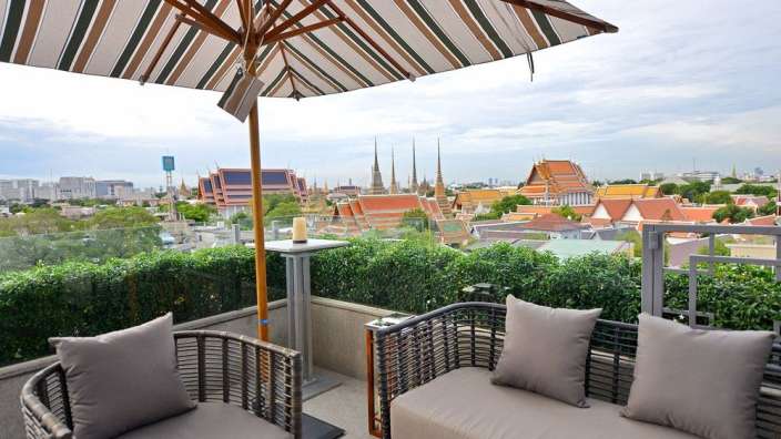 Ein Balkon mit einer Couch und Stühlen und einem Regenschirm