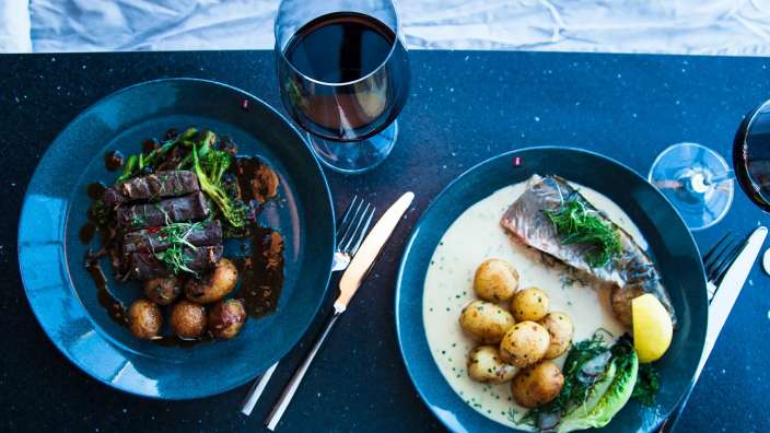 Zwei Teller mit Essen und ein Glas Wein auf einem Tisch