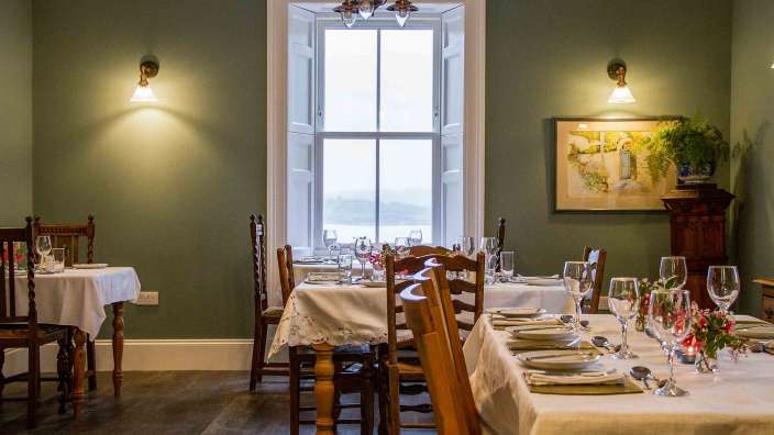 Ein Esszimmer mit Tischen und Stühlen und einem großen Fenster