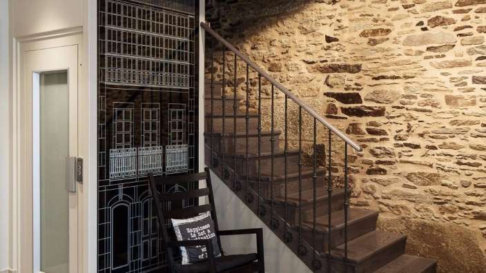 Ein Schaukelstuhl mit einem Kissen darauf steht neben einer Treppe