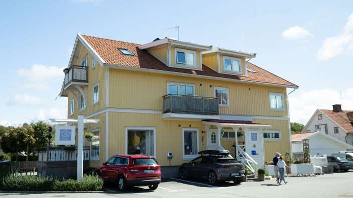 Ein gelbes Haus mit einem roten Auto vorne geparkt