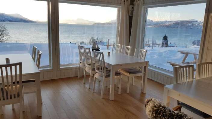 Ein Esszimmer mit einem Tisch und Stühlen mit Blick auf den Ozean