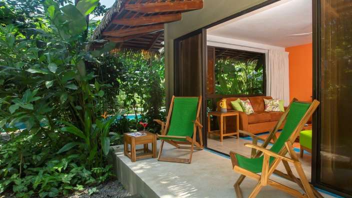 Zwei grüne Stühle stehen auf einer Terrasse neben einem braunen Sofa