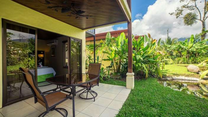 Ein Tisch und Stühle stehen auf einer Terrasse neben einem Bett