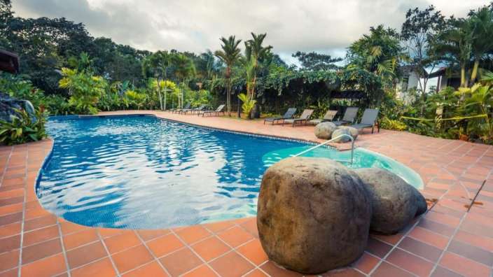 Ein großer Swimmingpool umgeben von Stühlen und Bäumen