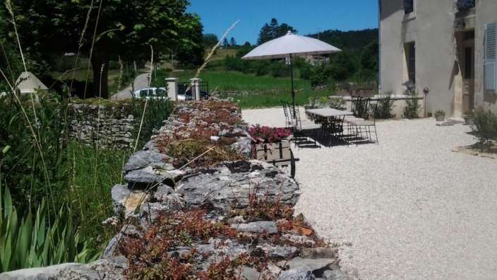 Eine Terrasse mit Tisch und Stühlen und einem weißen Sonnenschirm
