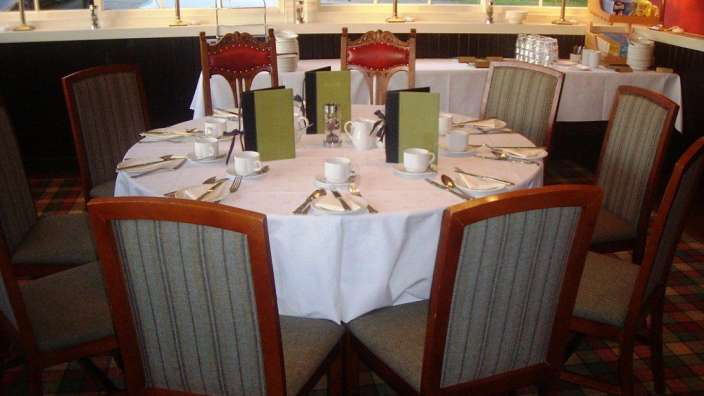 Ein runder Tisch mit einem weißen Tischtuch und Stühlen