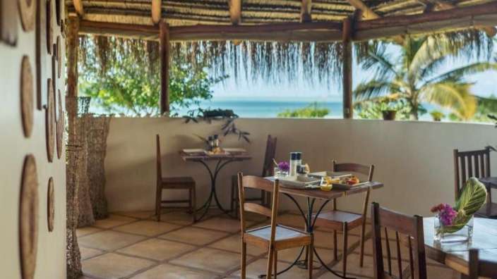Tische und Stühle auf einer Terrasse mit Blick auf das Meer