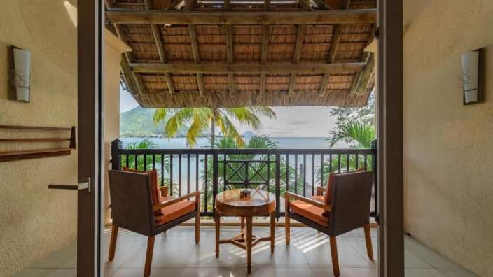 Ein Balkon mit zwei Stühlen und einem Tisch mit Blick auf den Ozean