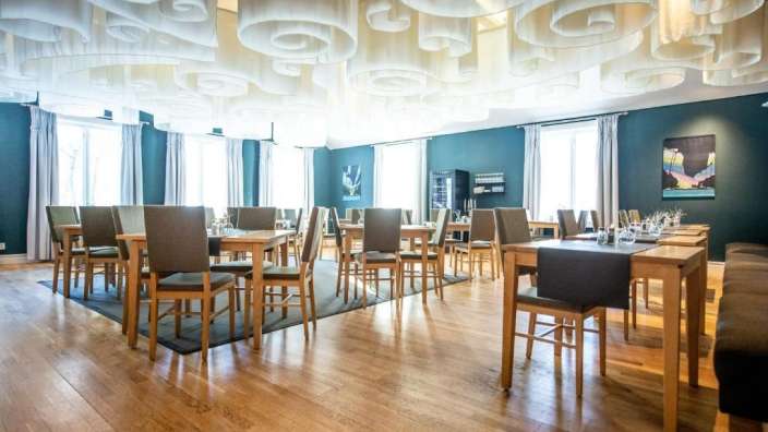 Ein Esszimmer mit vielen Tischen und Stühlen