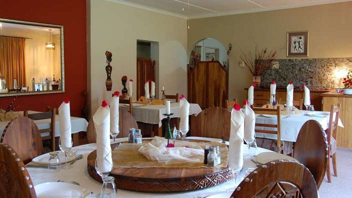 Ein Esszimmer mit Tischen und Stühlen und einem Spiegel