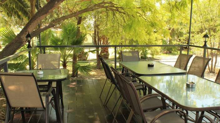 Ein Tisch und Stühle auf einem Deck mit Bäumen im Hintergrund