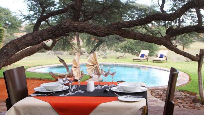 Ein Tisch mit Tellern und Gläsern vor einem Pool