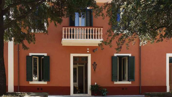 Ein rotes Haus mit grünen Fensterläden und einem Balkon