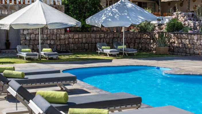 Ein Swimmingpool mit Liegestühlen und Sonnenschirmen umgeben