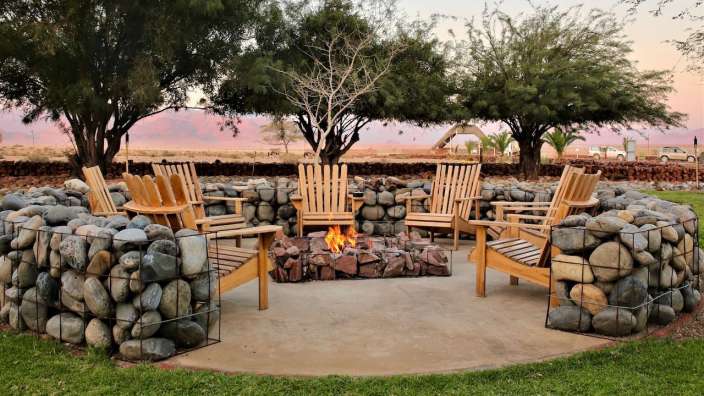 Eine Gruppe von Holzstühlen sitzt um einen Feuerplatz