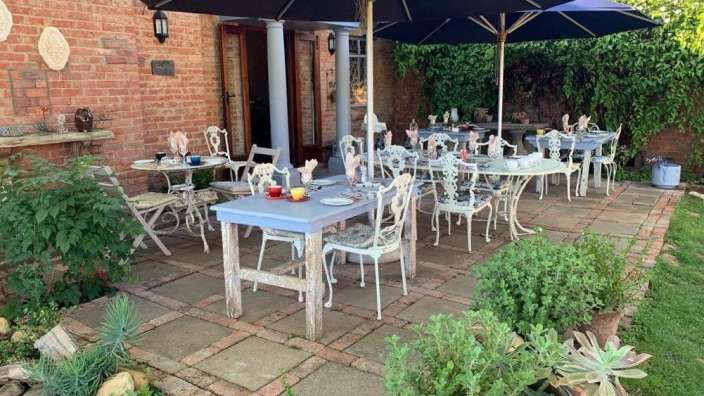 Eine Terrasse mit Tischen und Stühlen und Sonnenschirmen vor einem Backsteingebäude