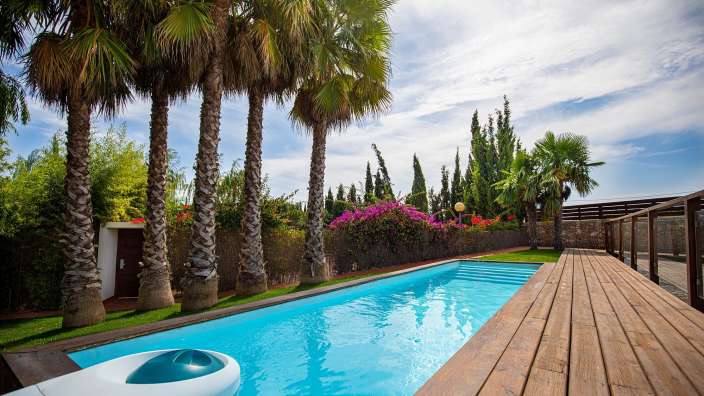 Ein großer Swimmingpool umgeben von Palmen und einem Holzdeck