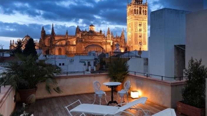 Liegestühle und ein Tisch auf einer Terrasse mit einer Kathedrale im Hintergrund