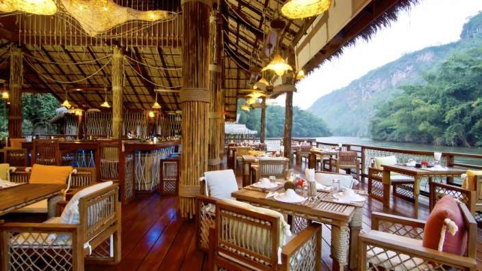 Ein Restaurant mit Tisch und Stühlen mit Blick auf einen Fluss
