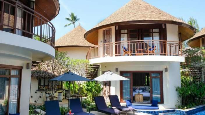 Ein Haus mit einem Pool und Liegestühlen davor