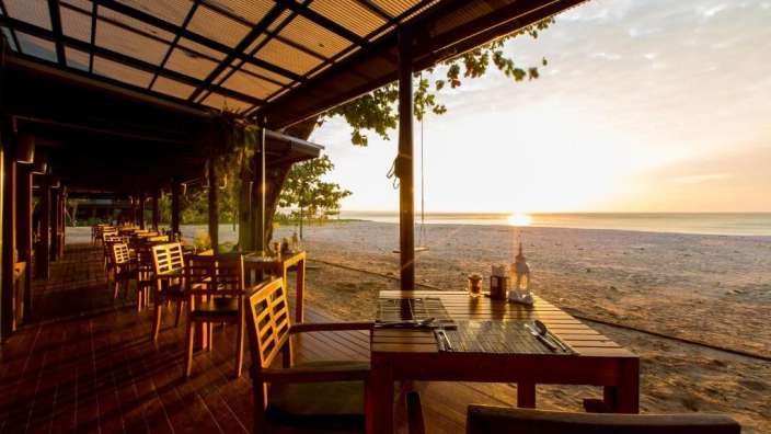 Tische und Stühle auf einer Terrasse mit Blick auf den Strand