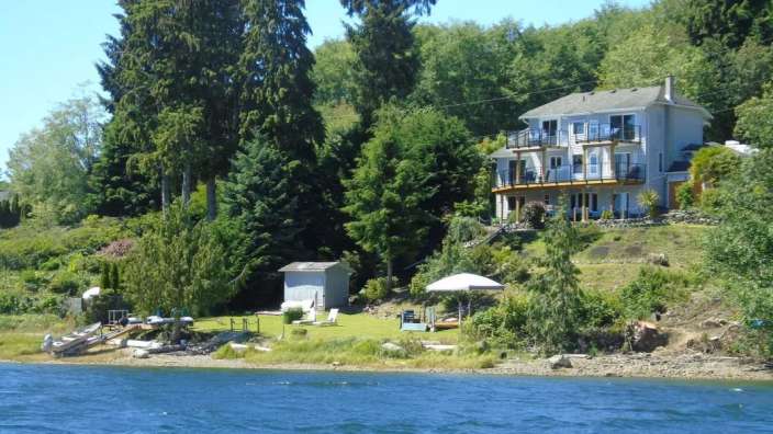 Ein großes Haus sitzt auf einem Hügel über einem See