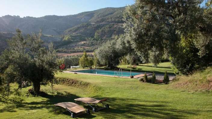 Ein großer Pool in einem grünen Feld mit Blick auf die Berge