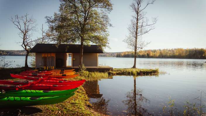 Eine Reihe von bunten Kajaks steht neben einem See