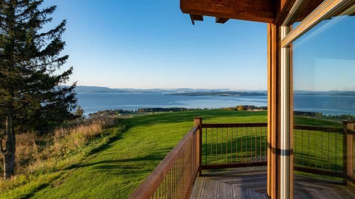 Ein Balkon mit Blick auf einen See und eine grüne Wiese