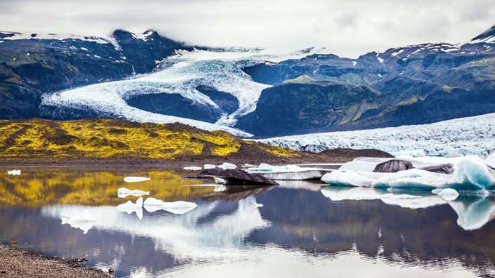 Ein See mit Eisbergen und Bergen im Hintergrund