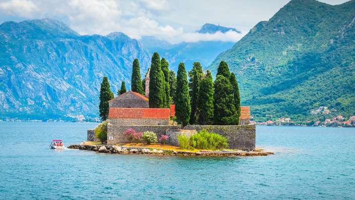 Eine kleine Insel mit einer Kirche und Bäumen inmitten eines Sees