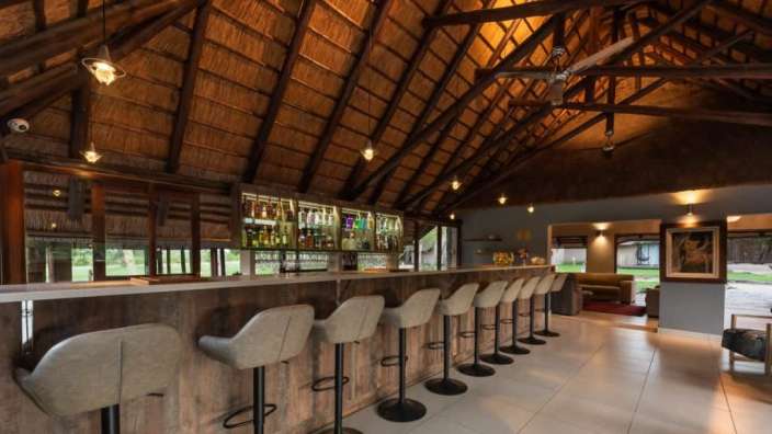 Eine lange Bar mit Stühlen und einem Strohdach