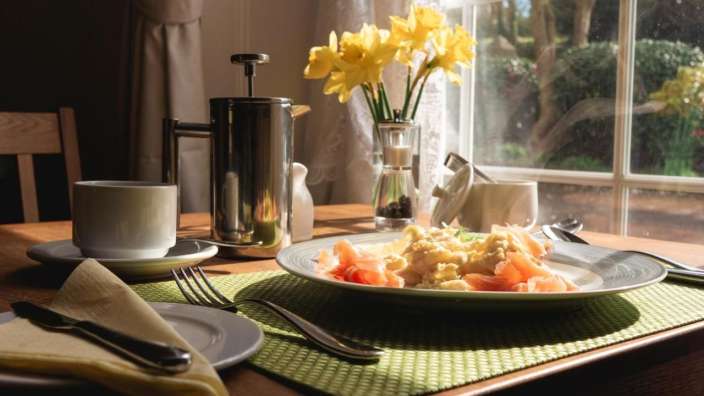 Ein Tisch mit einem Teller mit Essen und einer Vase mit Blumen darauf