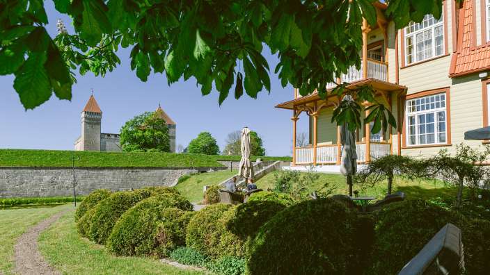 Ein Haus mit einem roten Dach sitzt auf einer grünen Wiese