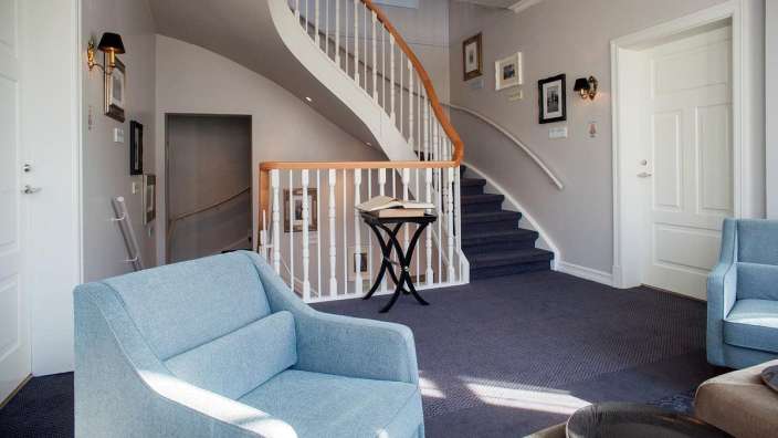 Ein blauer Stuhl sitzt in einem Flur neben einer Treppe